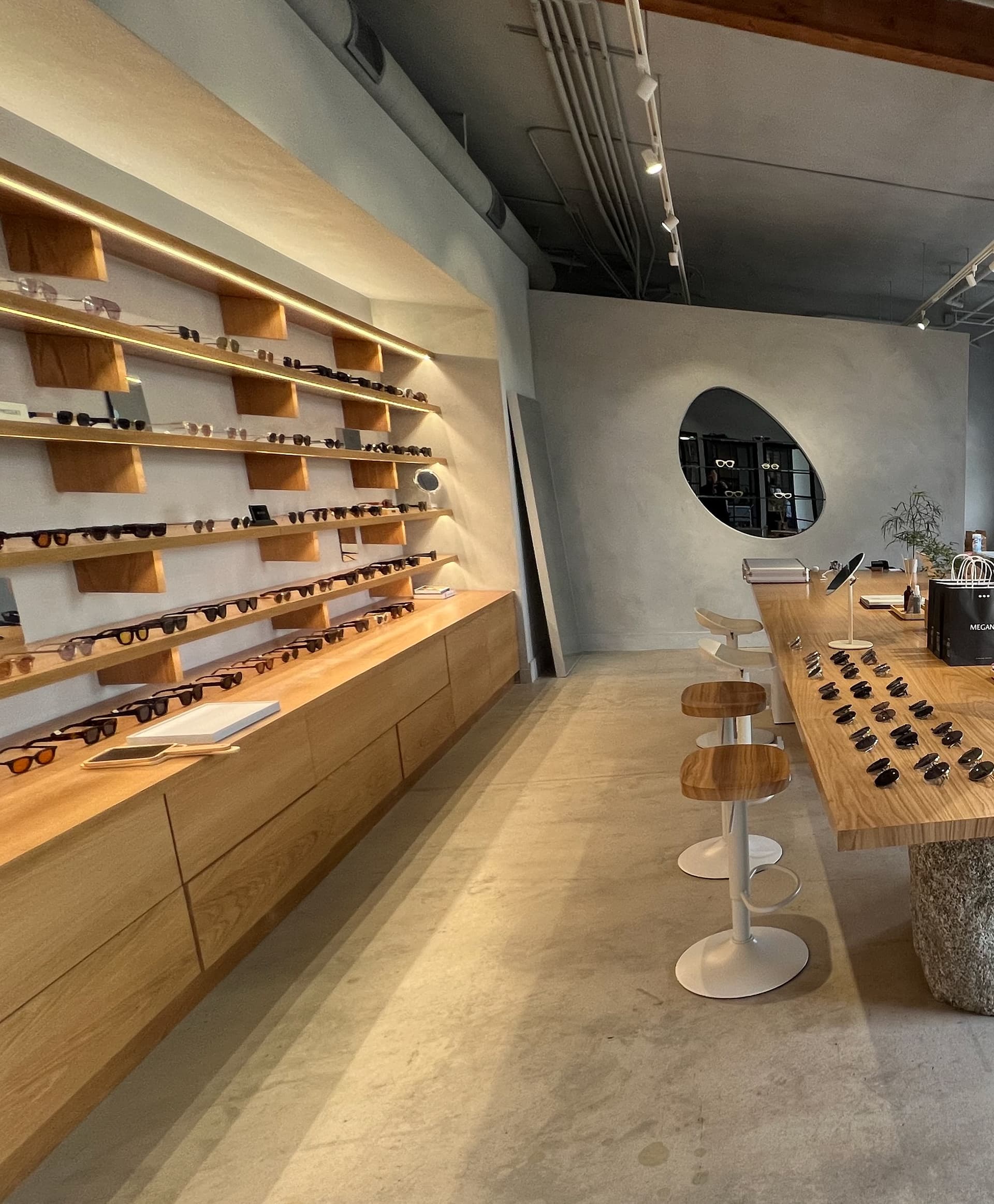 Megane: An eyewear retail space in concrete and warm oak.